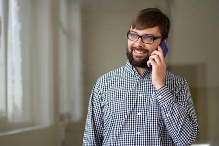 Close-up portrait of a young man who speaks on the phone positive and smiles
