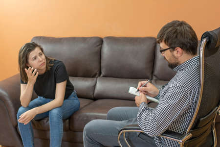 Psychotherapist doctor writes notes about a womans anxious depression during a psychotherapy sessionの写真素材