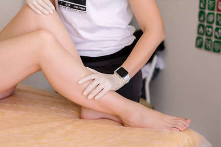 Close-up of female beautiful smooth legs after depilation, the master stands nearby