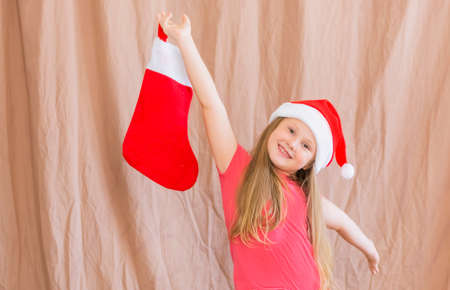 Girl celebrates new year and christmas wearing santa claus hat with christmas sock copy space