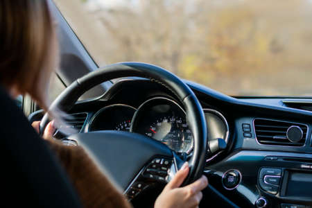 Photo without a face woman in the car holding the wheel of the blur can be seen the instrument of...
