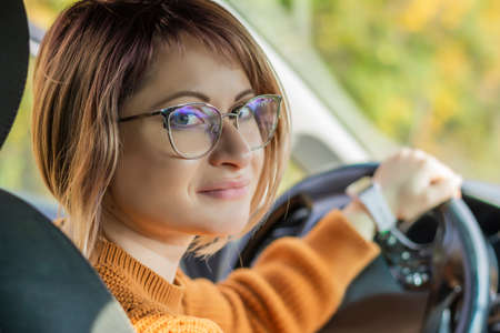 Car rental close-up beautiful woman sitting in the car holding the wheelの写真素材