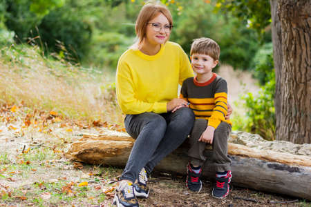 Picnic in the forest in autumn mom and son in cozy sweaters look directly at the camera