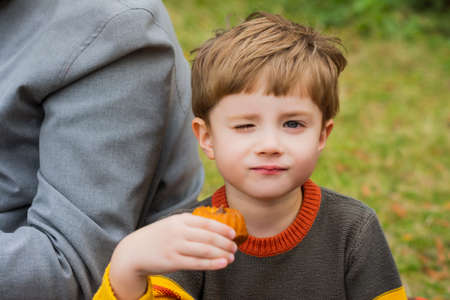 Close-up portrait of a little boy in a sweater eating in natureの写真素材