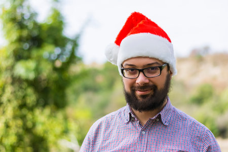 Portrait of a smiling man in a plaid shirt wearing a santa claus hatの写真素材