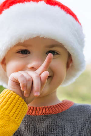 Close-up boy in cozy knitted sweater wearing santa hat outsideの写真素材