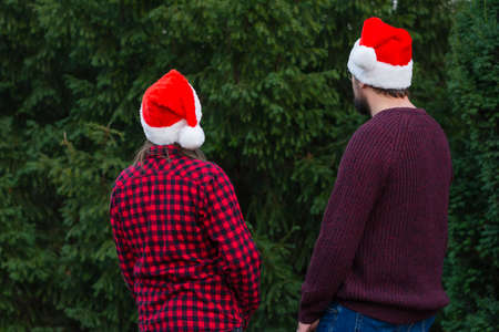 Back view couple in christmas santa hats celebrate Merry Christmas tree outdoors copy Black Fridayの写真素材