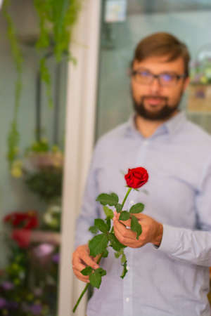 Gift background for a postcard for valentines day a man in a blur holding a red rose in his handsの写真素材