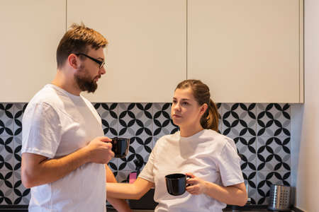 Cheerful young couple two friends drinking coffee or tea in the morning at home in the kitchen relaxの写真素材