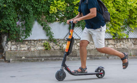 Young man no face on vacation rides electric scooter around the city in the park in summerの写真素材