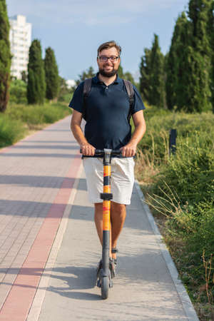 Handsome riding an electric scooter travelling through the city park healthy lifestyle eco-friendly