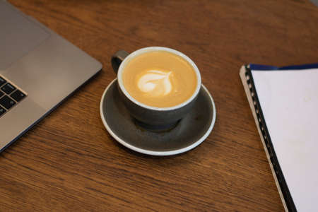 Cup of art latte or cappuccino coffee on wooden background in a cafe copy spaceの写真素材