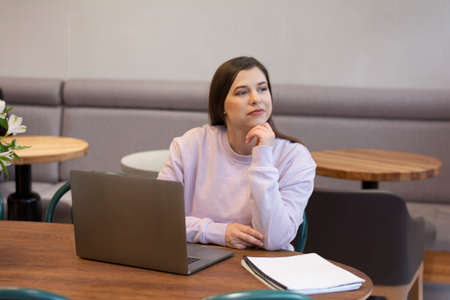 Young female freelancer working on laptop sitting in cafeの写真素材