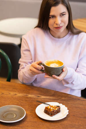 Enjoying morning routine beautiful millennial woman drinking coffee or hot drinks in cafe aloneの写真素材