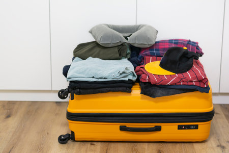 Closed orange plastic suitcase on top of it neatly folded mens clothesの写真素材