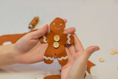 Gingerbread man with red bow and wooden felt buttons homemade in handsの写真素材