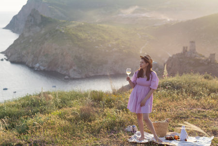 Woman enjoys white wine among the mountains background natureの写真素材