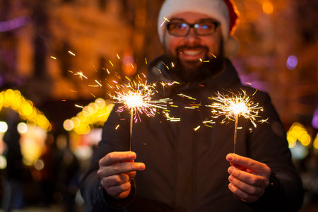 Happy man celebrates Christmas with sparklersの写真素材