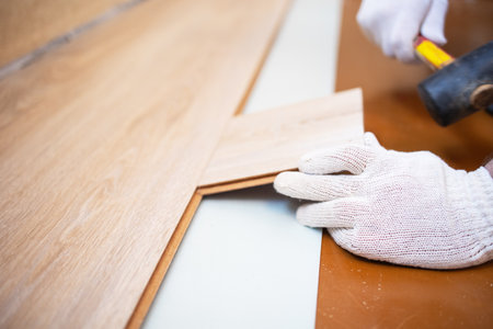 Master rubber mallet knocks on the laminate in the process of layingの写真素材