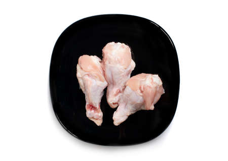 Fresh raw chicken isolated in black plate on white backgroundの写真素材