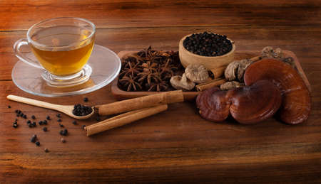 Tea, lingzhi, black pepper, cinnamon, star anise on woodの写真素材