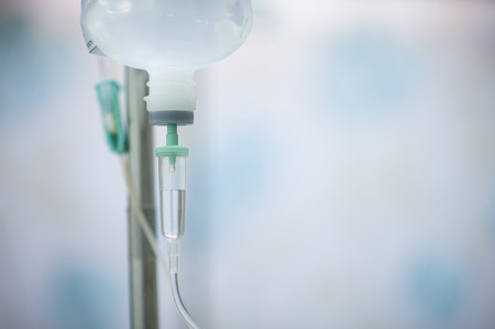 A bottle of saline is hung on the rail to pass through the hose for treating the patient.の写真素材