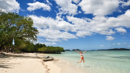 Single young bikini girl jumps on white beachの写真素材