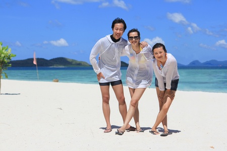 Front Portrait of three happy friends standing on tropical white beach, with background of beautiful blue sky and cloud and ocean. Shot on Pass Island, Coron, Palawan, Philippinesの写真素材