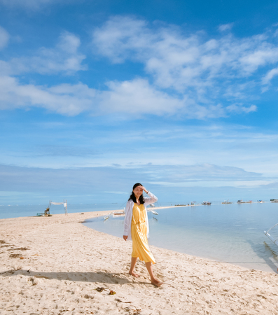  Single young girl looking at the camera when walking on long curving stretch of narrow white sand beach during low tides  Shot on Virgin Island, Panglao, Bohol, Philippines, known to many locals as the ?hidden oasis? の写真素材