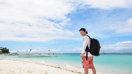 Portrait of single young male backpacker in white shirt and short pants looking back at camera on tropical beach  Shot on Pamilacan Island, Bohol, Philippines  の写真素材