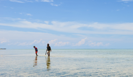 Semporna, Malaysia - Oct 3, 2014   two Bajau brother and sister hunting fish together  in shallow water on the beach, shot on Mabul island, Semporna, Sabah, Maylaysia  Bajau people are also referenced as the last sea gypsies,  sea-oriented, boat-dwelling,のeditorial素材