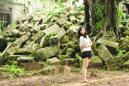 young girl sits in ancient rubbles, smiling at camera,  Angkor Wat, Camobdiaの写真素材