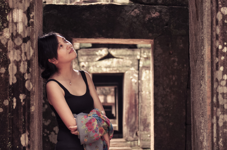 single young woman leans on pillars of ancient doorframe, smiling, looking aside,  Angkor Wat, Camobdiaの写真素材