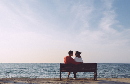 back portrait of young couple looking at each other on bench by the sea in Kusadas, Turkey, clean compositionの写真素材