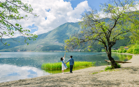 Young Chinese couple having fun while walking along the bank of Lugu lake hand in hand, at Daluoshui village, Lijiang, Chinaのeditorial素材