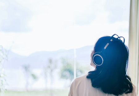 Single young Chinese woman looking to the sky with headphones on the headの写真素材