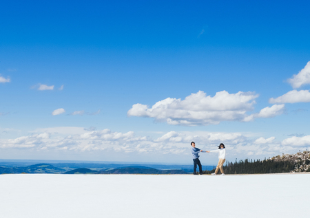 Young Asian couple walks together hand in hand on snow at edge of Schafberg mountain  , Austriaの写真素材