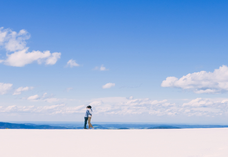 Young Asian couple hold each other, standing on snow at edge of Schafberg mountain , Austriaの写真素材