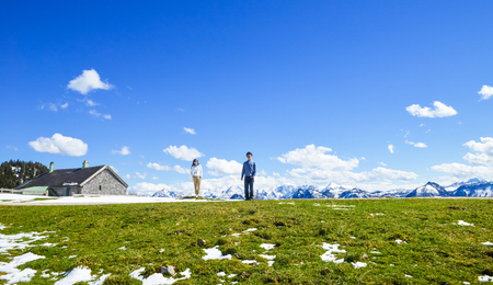 Young Asian couple stand at edge of Schafberg mountain , Austria , looking at cameraの写真素材