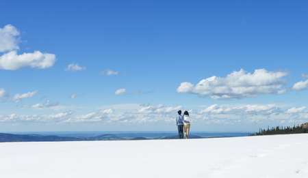Young Asian couple hold each other, standing on snow at edge of Schafberg mountain  , Austriaの写真素材