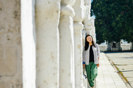 single Asian girl leans on white pagoda at Kuthodaw Pagoda, Mandalay, Myanmarの写真素材