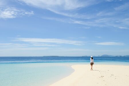 single young Asian girl walking on tropical white sand beach, at Pulau Sibuan, Semporna, Sabah, Malaysiaの写真素材
