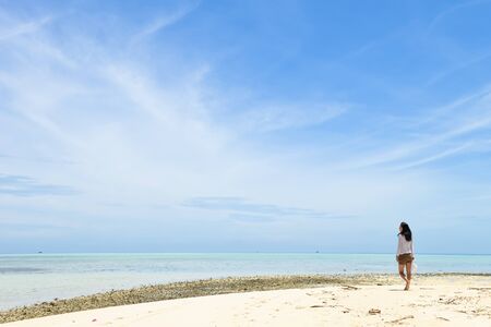 single young Asian girl walking on tropical white sand beach, at Pulau Sibuan, Semporna, Sabah, Malaysiaの写真素材