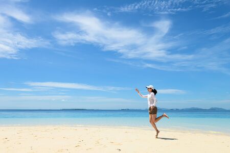 single young girl on tropical white sand beach running toward horizon. Semporna, Sabah, Malaysiaの写真素材