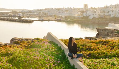 Single Asian girl sits among blossomed flowers when sunrise in Spring season on Paros island, Greeceの写真素材