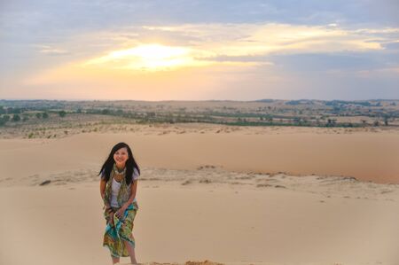 Single Asian girl smiling to camera on Red Sand Dune when daybreak at Muine, Vietnamの写真素材
