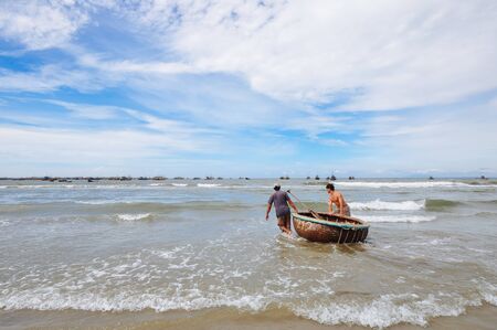 Muine / Vietnam - Oct 2011 : Two local men walking into the sea with traditional fishing basket at Muine, Vietnamのeditorial素材