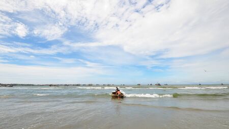 Two local men walking into the sea with traditional fishing basket at Muine, Vietnamの写真素材