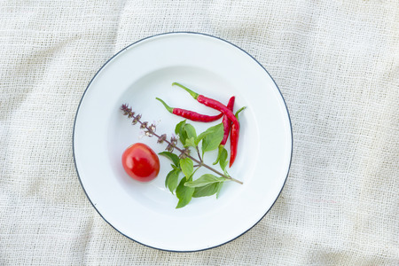 basil chili and tomato on white fabric backgroundの写真素材