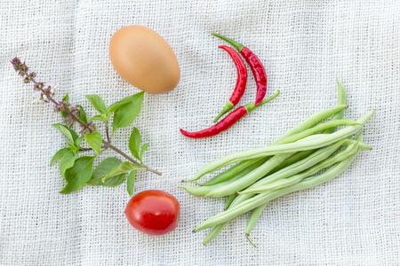 basil chili egg and tomato on white fabric backgroundの写真素材